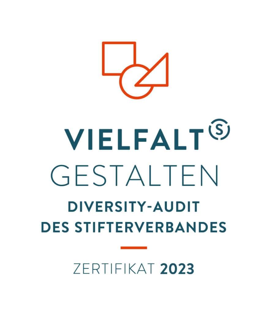 Das Logo für das Zertifikat mit dem Titel "Vielfalt Gestalten". Es handelt sich um das Diversity-Audit des Stifterverbandes, das im Jahr 2023 ausgestellt wurde. Oben ist ein orangefarbenes Symbol mit geometrischen Formen (Quadrat, Kreis und Dreieck) abgebildet. Darunter steht der Text "Vielfalt Gestalten" in großen Buchstaben, gefolgt von "Diversity-Audit des Stifterverbandes" und "Zertifikat 2023".