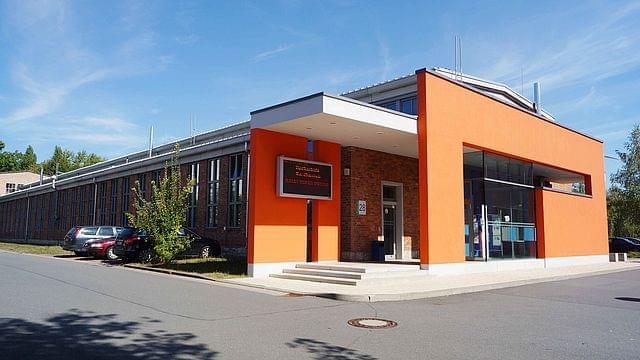 Vorderansicht des AKI-Gebäudes. Die Front in einem kräftigen Orangeton.