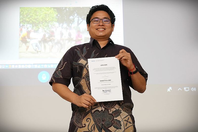 International student at Nordhausen University of Applied Sciences proudly presents his certificate for the DAAD prize at an event.