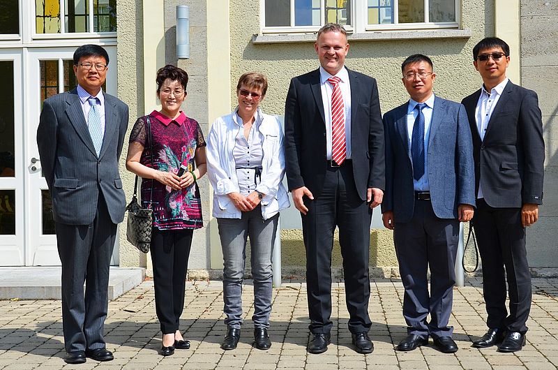 Internationale Gäste und Hochschulvertreter*innen stehen gemeinsam vor einem Gebäude der Hochschule Nordhausen.