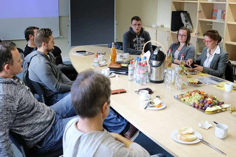 Eine Gruppe Personen sitzt um einen Tisch herum.