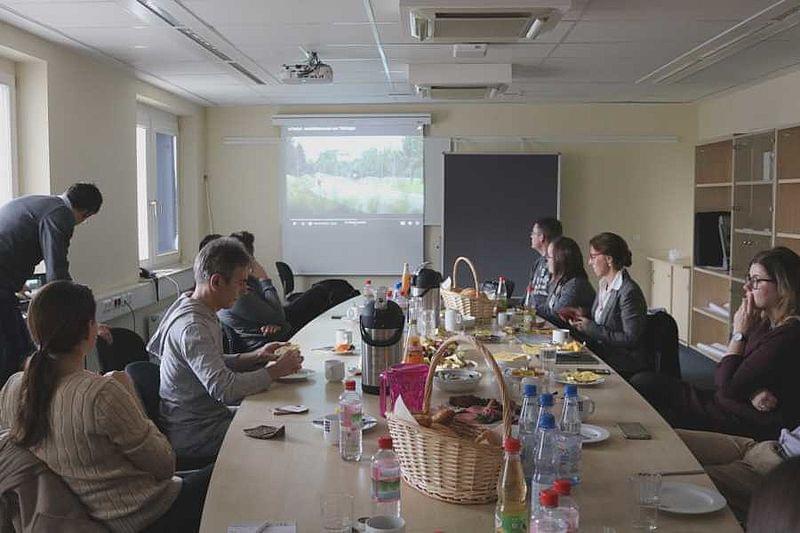 Eine Gruppe Personen sitzt um einen Tisch herum. Auf dem Tisch steht ein Korb.