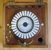 Blick von oben auf einen Zeigertelegrafen. Der Apparat befindet sich in einem quadratischen hölzernen Kasten mit Deckel, welcher hier geöffnet ist.