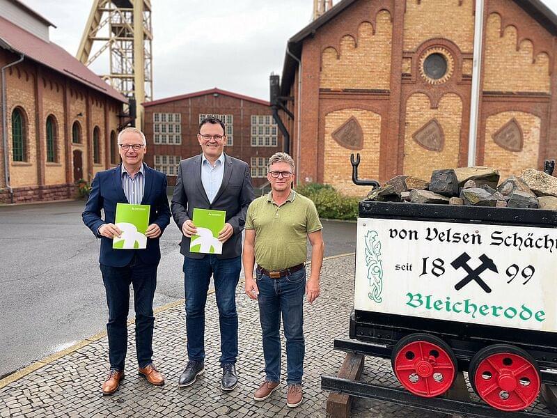 drei Personen vor einem Industriegelände