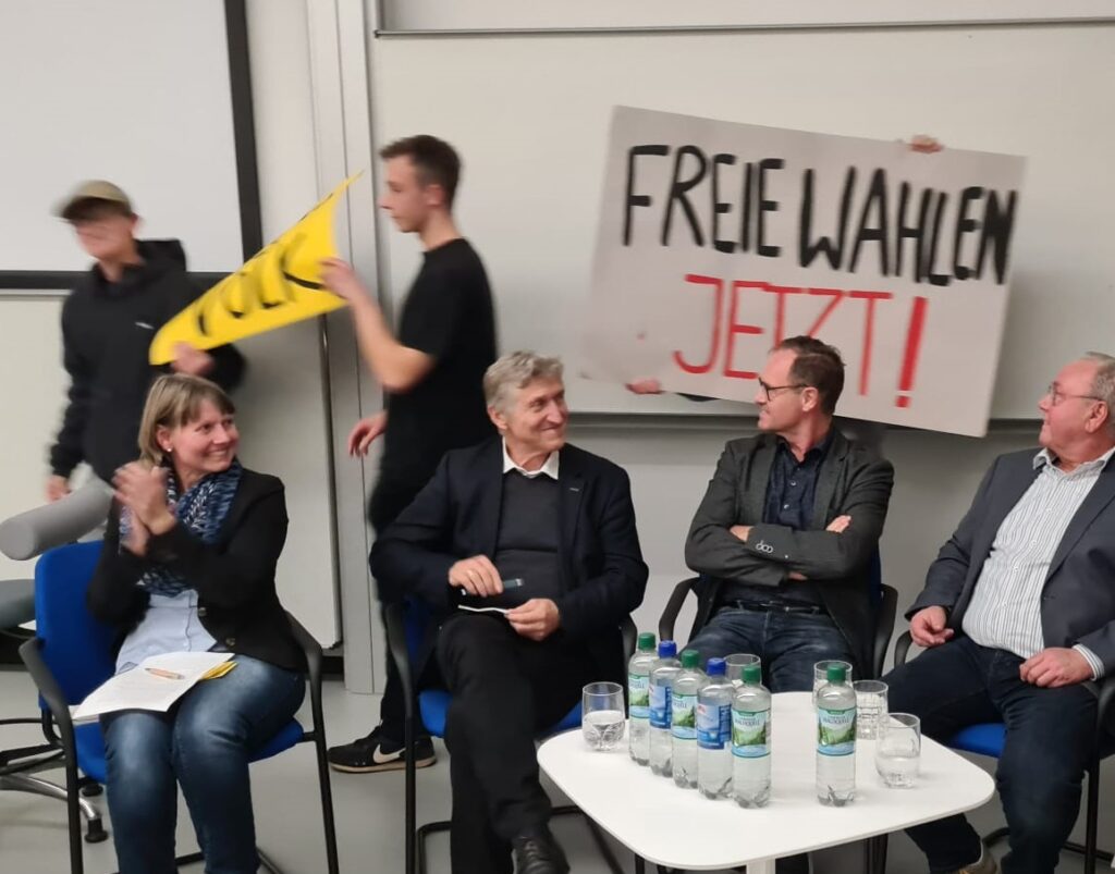 Panel discussion at Nordhausen University of Applied Sciences: contemporary witnesses and guests discuss the importance of free elections, while committed students bring the atmosphere of the 1989 demonstrations to life with re-enacted banners.