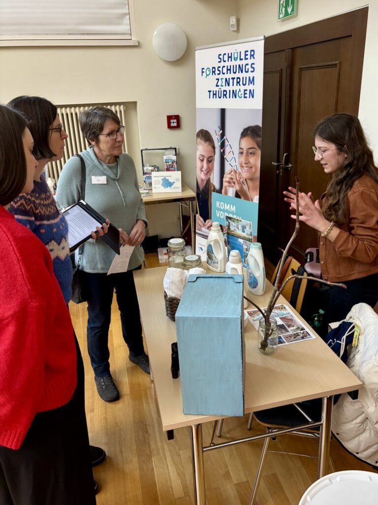 Eine Szene mit mehreren Menschen an einem stand mit einem projektexponat.
