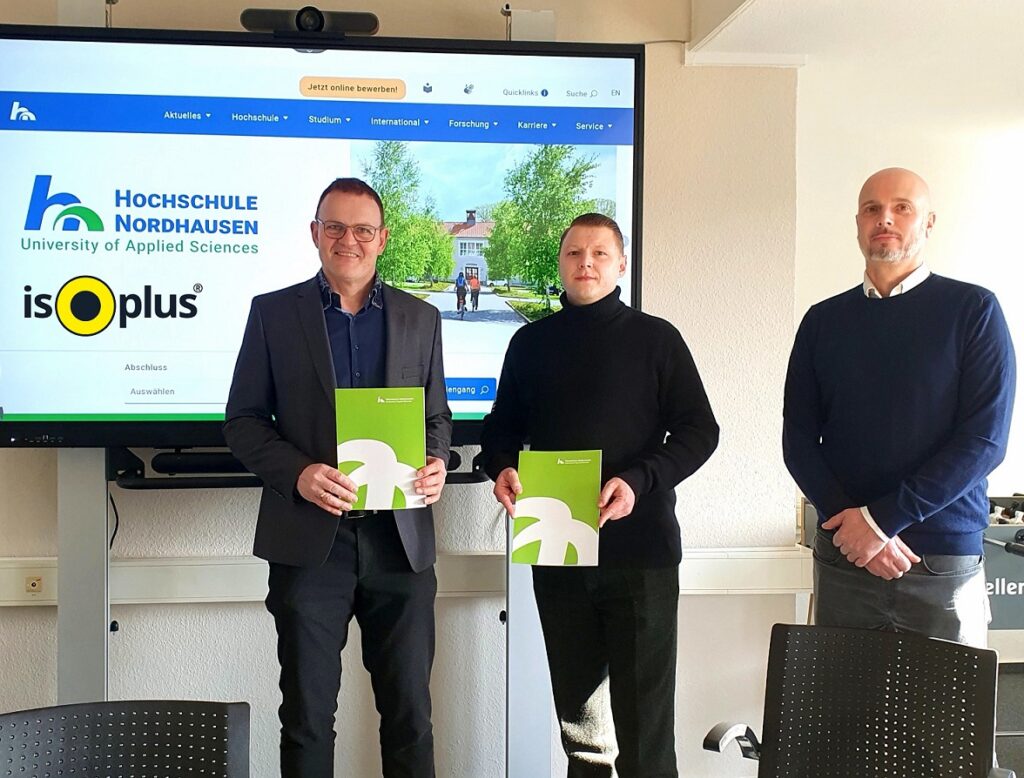 3 men with certificates in front of a projection with logos