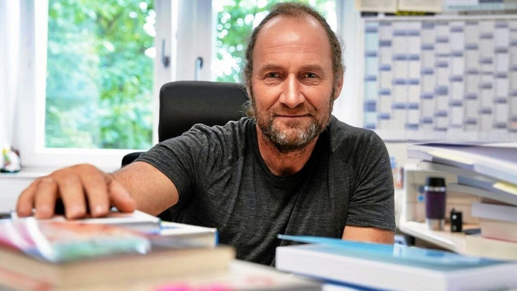 a man sitting at a desk with a stack of books