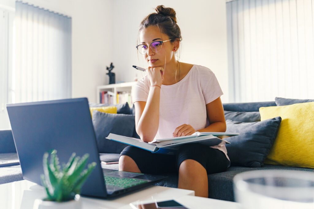 a woman sitting on a couch with a laptop and a book