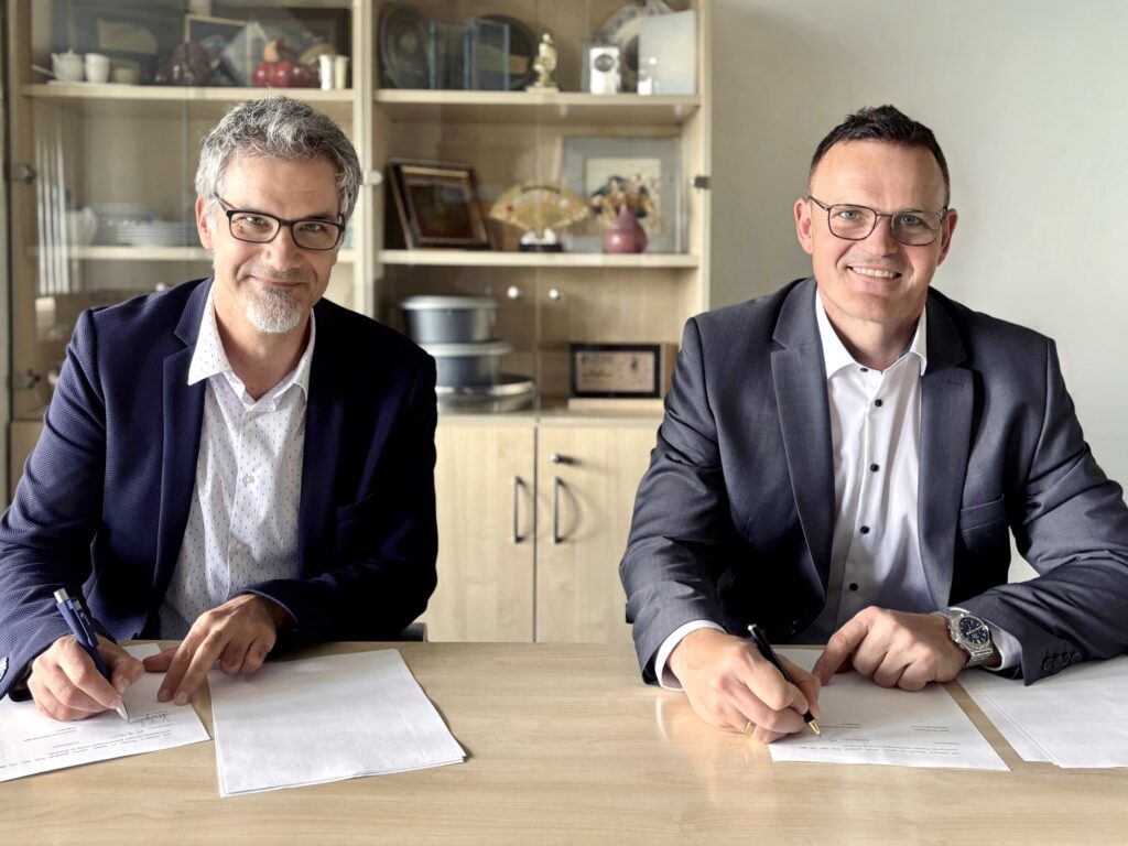 Zwei Personen unterzeichnen ein Dokument.