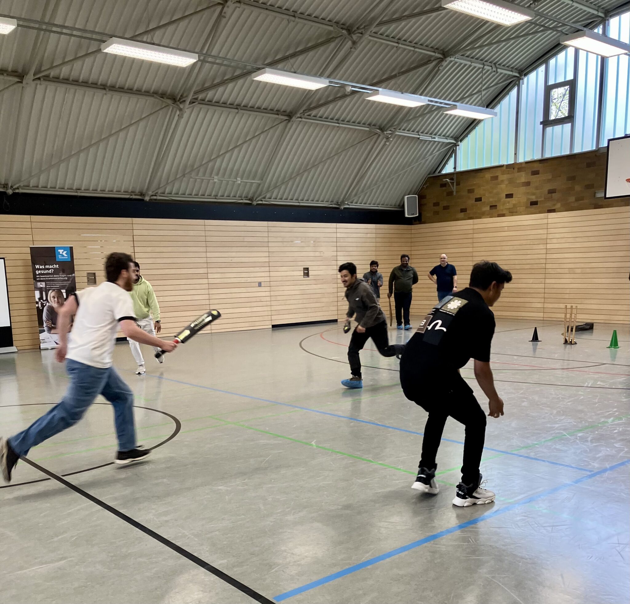 People playing cricket in the hall.