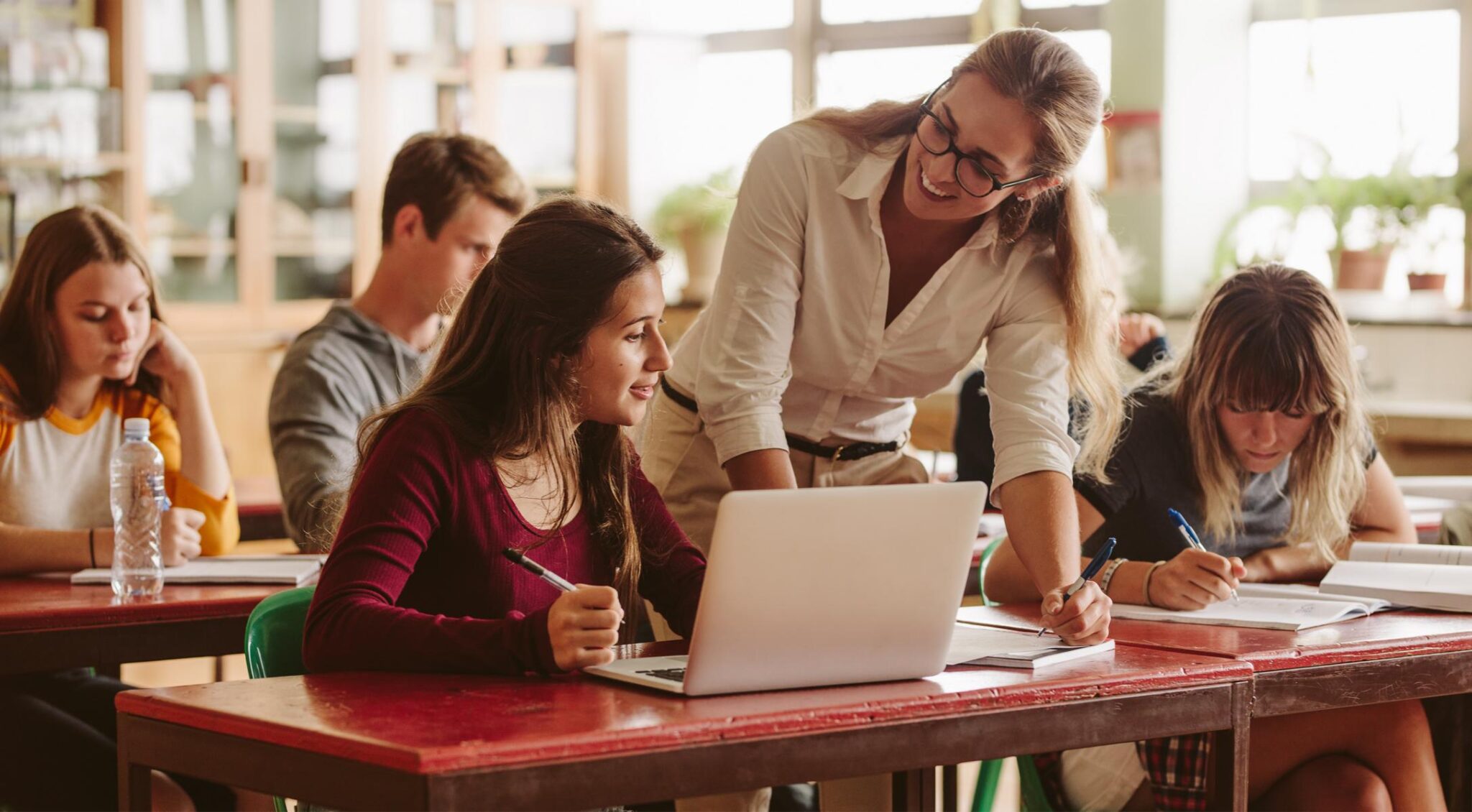 Schüler lernen mit Lehrerin am Tisch.