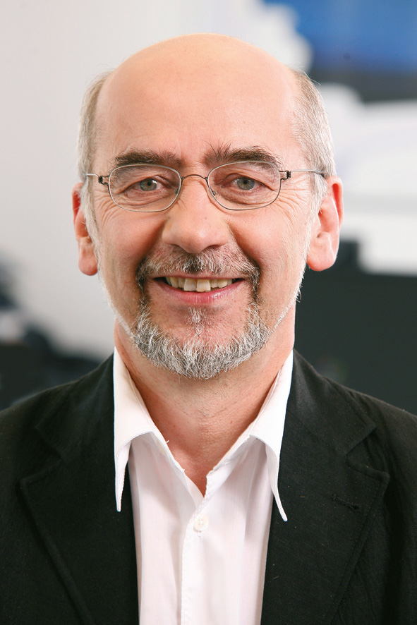 An older man with a bald head, glasses and a grey beard, wearing a white shirt and a black jacket. He smiles at the camera and is the co-author of the marketing textbook.