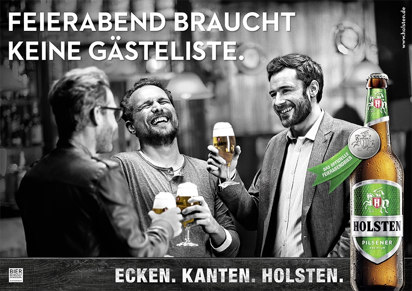 The advert shows a blurred, atmospheric bar scene in black and white in the background. Three men aged between 30 and 40 are laughing heartily and clinking glasses of beer. Above the scene is the text in large, white capital letters: „FEIERABEND BRAUCHT KEINE GÄSTELISTE.“. At the bottom is a dark bar with the slogan „ECKEN. EDGES. HOLSTEN.“ completes the picture. In the bottom right-hand corner is a coloured Holsten Pilsener bottle with drops of water (condensation), marked with a green banner „THE OFFICIAL CELEBRATION EVENING BEER“.