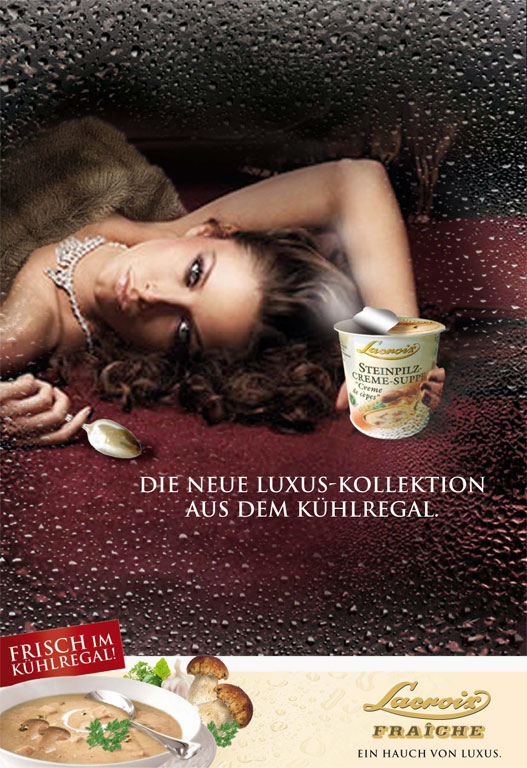 The motif is photographed through a pane of glass fogged with water droplets, creating a chiller cabinet atmosphere. Behind it is a woman wearing a fur stole and jewellery on a dark red background; she is holding a cup of Lacroix cream of porcini mushroom soup. In the centre of the picture is the text: „THE NEW LUXURY COLLECTION FROM THE KÜHLREGAL.“. At the bottom, a white bar shows a ready-to-serve bowl of soup, fresh porcini mushrooms and the logos „Lacroix FRAÎCHE“ and the slogan „EIN HAUCH VON LUXUS.“.
