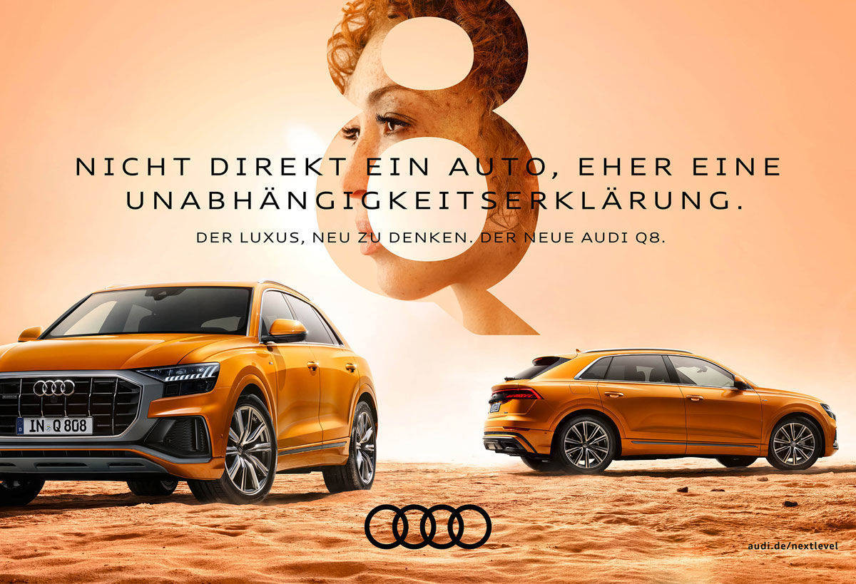 The advert shows two perspectives of an orange and gold Audi Q8 in a sandy desert landscape under a bright, warm sky. In the foreground, the front section can be seen diagonally from the left, with the side and rear views in the background. A large, transparent number „8“ is placed in the centre of the upper third of the image, in which the portrait of a woman appears in profile. The text reads: „NOT DIRECTLY A CAR, BUT A DECLARATION OF INDEPENDENCE. THE LUXURY OF RETHINKING. THE NEW AUDI Q8.“