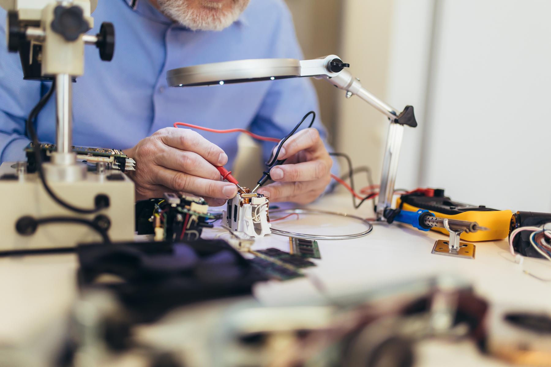 A man is repairing electronic devices at a table